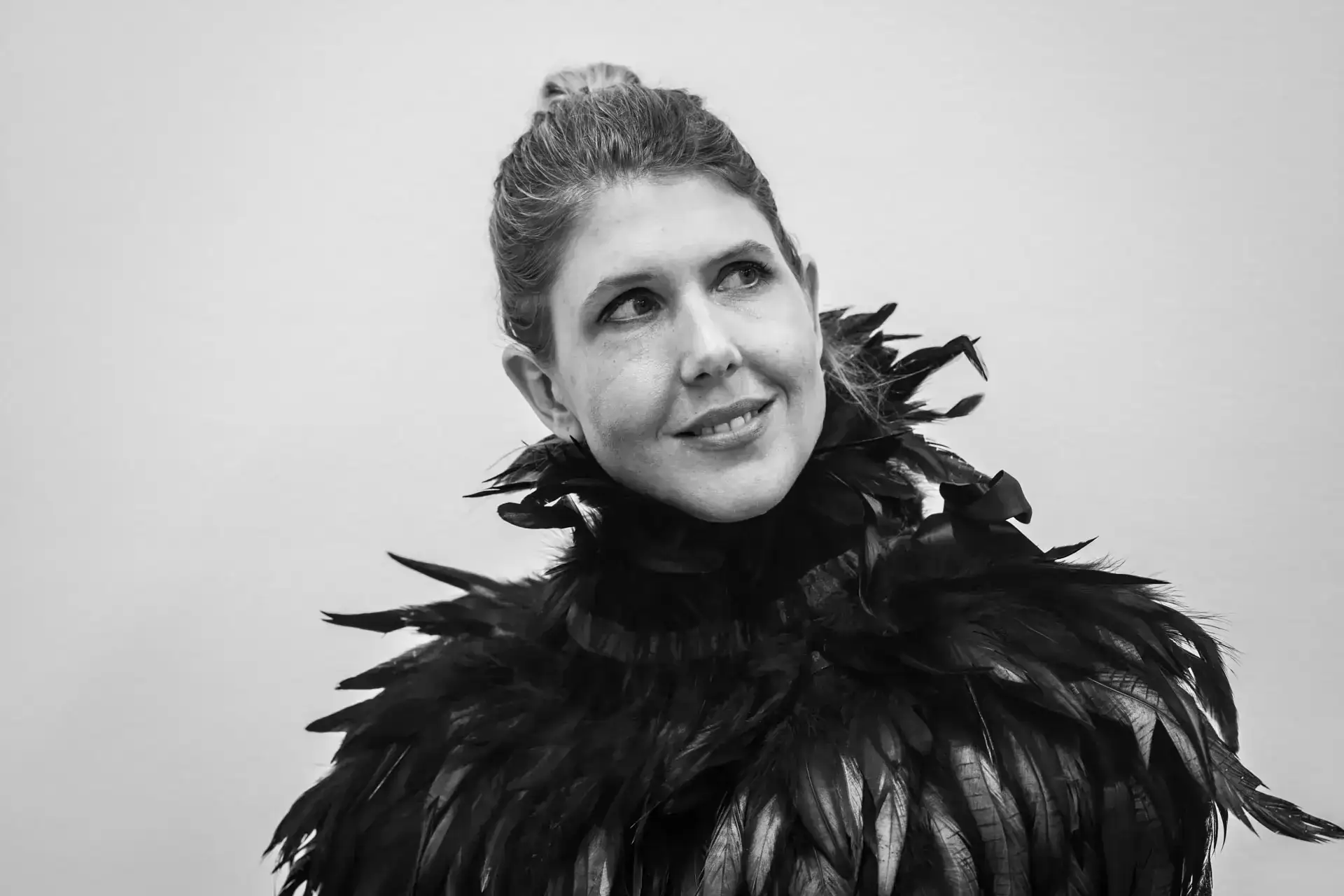 A woman wearing a black feather jacket and smiling.
